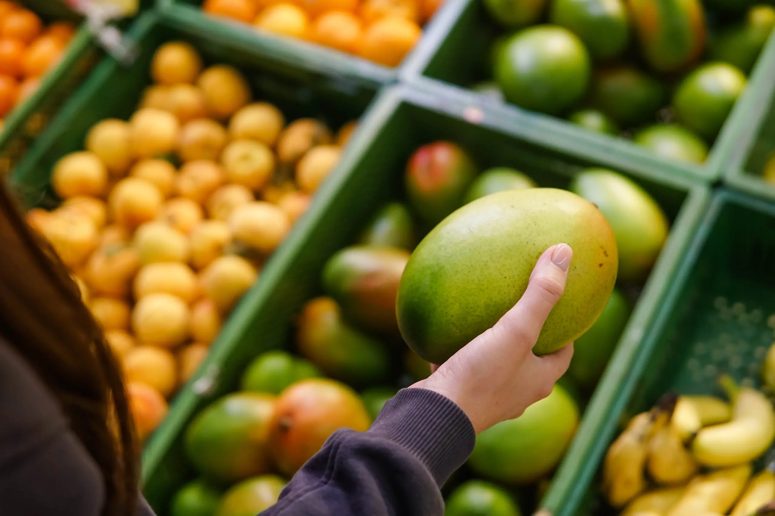 Woman,Choosing,Ripe,Mango,At,Supermarket